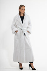 Full-length white mink fur coat featuring a wide notched lapel, cuffed sleeves, and a matching leather tie-belt cinched at the waist.