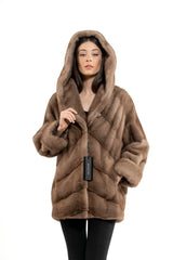 Pastel mink fur short jacket with a hood, featuring a V-chevron pattern on the body, wide sleeves, and a MANZARI brand tag.