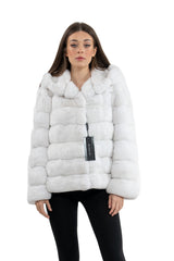 A front view of a white chinchilla fur jacket with a hooded collar, horizontal panel construction, and a branded Manzari hangtag attached.