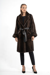 A dark brown mink fur jacket with vertical panels, a wide collar, wide cuffed sleeves, and a removable dark leather tie-waist belt.