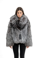A short silver natural fox fur jacket with a voluminous shawl collar, long sleeves, and a dense, shaggy texture in varying grey and black tones.