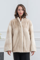 A short, cinnamon-colored mink fur jacket featuring a high collar and long, wide sleeves, shown from the front.