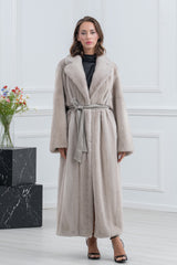 Pearl blue mink fur coat with wide lapels, long sleeves, and a matching fabric tie belt. Full-length silhouette with a smooth, vertical pelt.