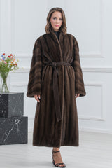 Brown mink fur coat featuring vertical panels, a wide shawl collar, and a matching fabric tie belt at the waist with wide, flowing sleeves.