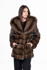 A Russian sable jacket in gun metal tones, featuring a large hood and horizontal fur panels, shown from the front with hands in side pockets.
