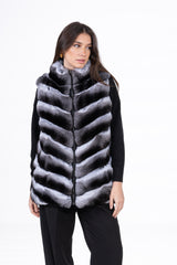 Reversible chinchilla fur vest with a black zip closure, featuring horizontal V-chevron patterned fur in natural grey and black tones.