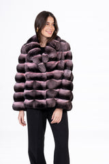 Short jacket made of chinchilla fur featuring horizontal panels of dark grey and pink powder, with a wide, rounded lapel collar.