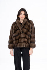 A short Russian sable jacket featuring a V-chevron pattern, a rounded collar, and long sleeves, worn over a black top and trousers.