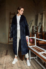 Long Swakara coat in blue-black with a wide lapel collar, featuring smooth horizontal-striped fur inserts on the sleeves.