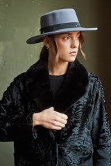 A black Swakara fur jacket with a distinctive flat, wavy texture and a wide, smooth contrast black fur lapel collar, worn open.