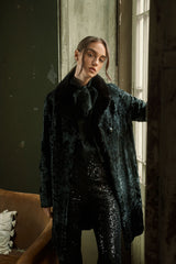 A long, black Swakara jacket with a flat, smooth black fur collar, showcasing the characteristic tight, rippled fur texture in an open front.