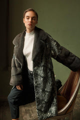 Swakara fur coat in dark green with a wide, solid grey mink collar and cuffs, featuring a subtle swirling pattern and an open front.