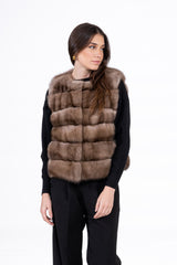 Short Russian sable vest in a light brown hue, featuring horizontal fur panels and a round neckline, worn over a black sweater.