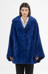 A royal blue mink jacket with an inverted V chevron pattern, a wide collar, and loose cape-style sleeves.