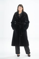 A black mink coat with an English collar and a matching tie belt, showing a straight, knee-length silhouette and deep side pockets.