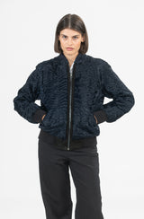 Short bomber jacket in dark blue Swakara with a ribbed collar, hem, and cuffs, featuring a central zip closure on a black panel.
