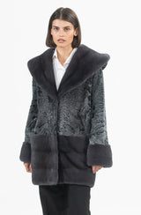Grey swakara coat featuring a large hood and sleeves with horizontal mink fur bands at the cuffs and lower body, over a white shirt.