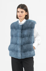 A blue mink vest with a horizontal paneled design, a collarless round neckline, and a simple front closure.