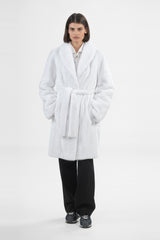 White mink coat with a large shawl collar and matching belted waist, featuring vertical fur panels and reaching mid-thigh.